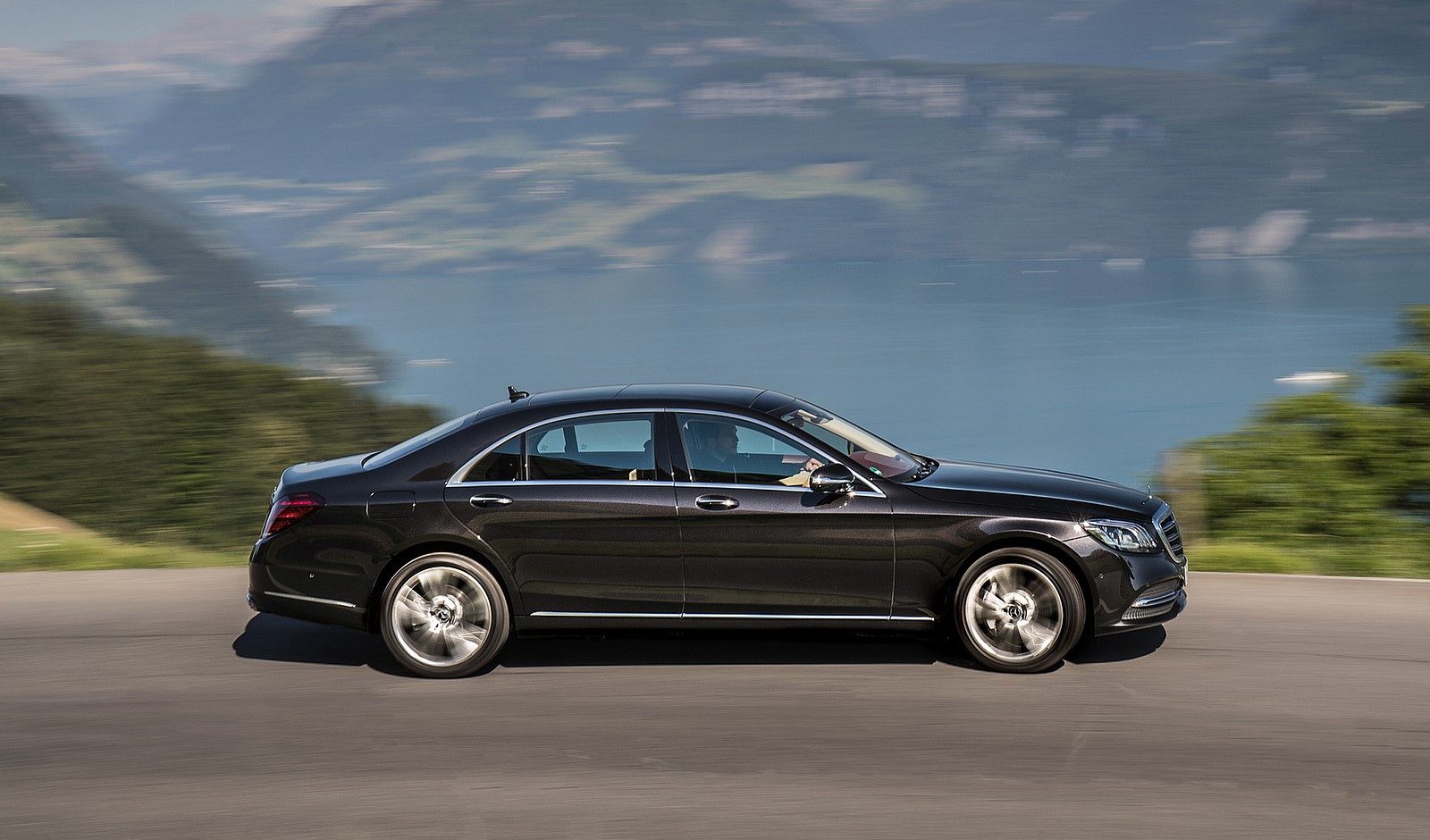 Black executive sedan travelling along a scenic lakeside road in Northern Italy